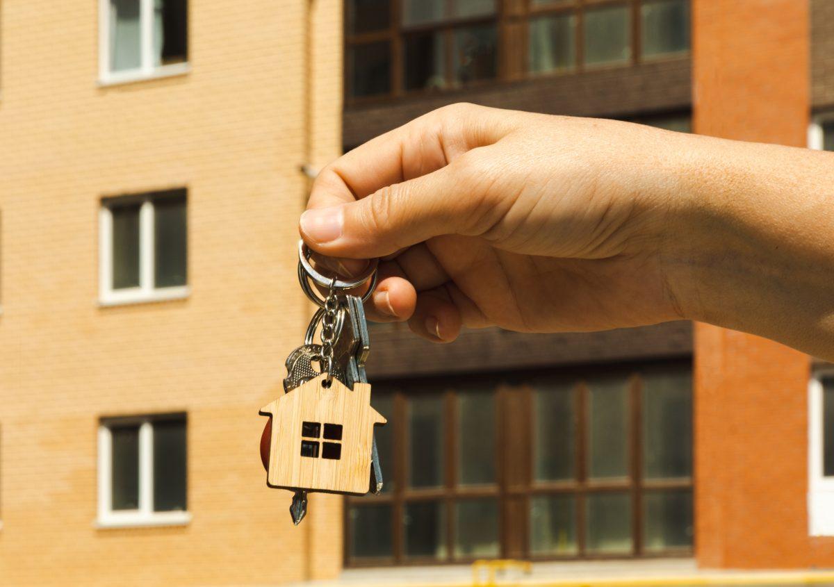 A woman holds the keys to a new quart or house. The keys open and close the door lock. The owner opens the door of a new house. The concept of selling and renting real estate.