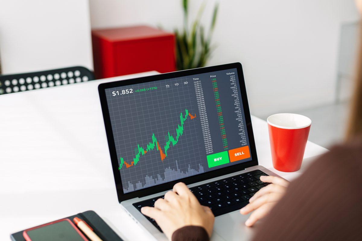 Young woman investor working on laptop at home. Female trader analyzing stock market. Trading online and investment concept.